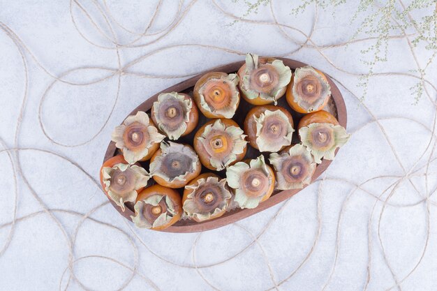 Plum dates in a wooden platter on grey surface