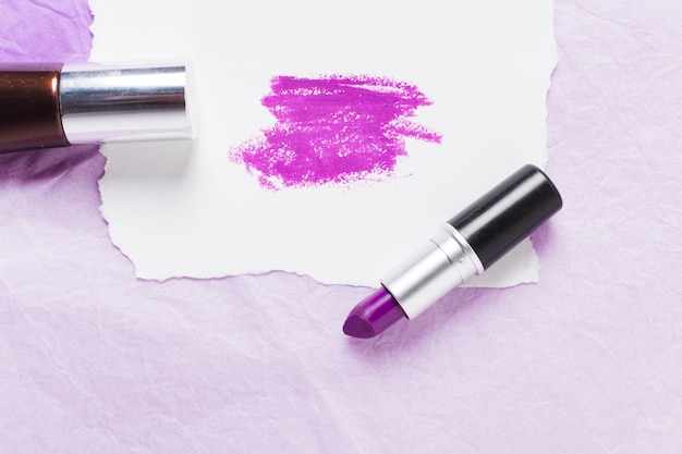 Plum lipstick with smears on paper sheet and nail polish