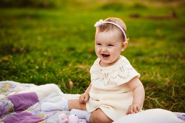 Plump little girl sits on white blanket 