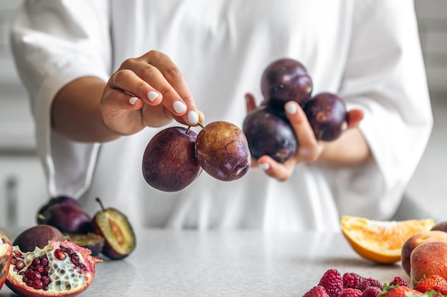 Free photo plums in the hands of a woman in the kitchen