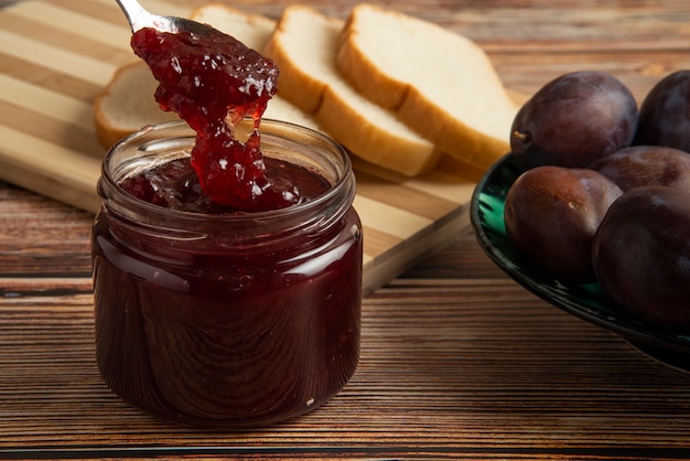 Plums with a jar of confiture and a toast bread.