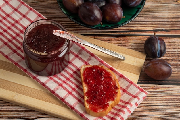 Plums with a jar of confiture and a toast bread.