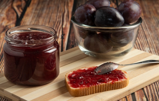 Plums with a jar of confiture and a toast bread.