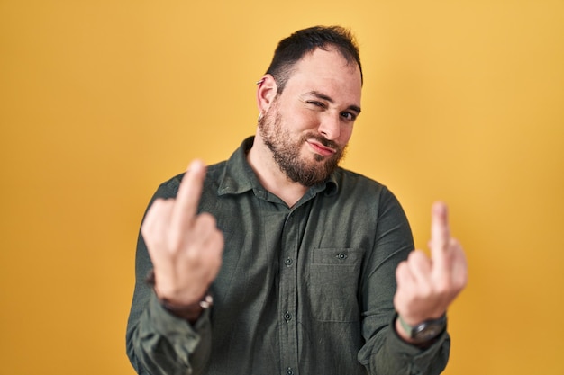 Free photo plus size hispanic man with beard standing over yellow background showing middle finger doing fuck you bad expression provocation and rude attitude screaming excited