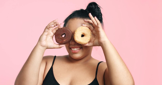 스튜디오의 플러스 사이즈 모델은 행복한 미소를 짓고 도넛을 먹습니다.