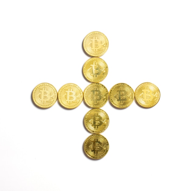 The plus symbol  laid out of bitcoin coins and isolated on white background