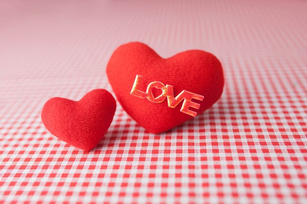 Plush hearts on a checkered tablecloth with the word "love"