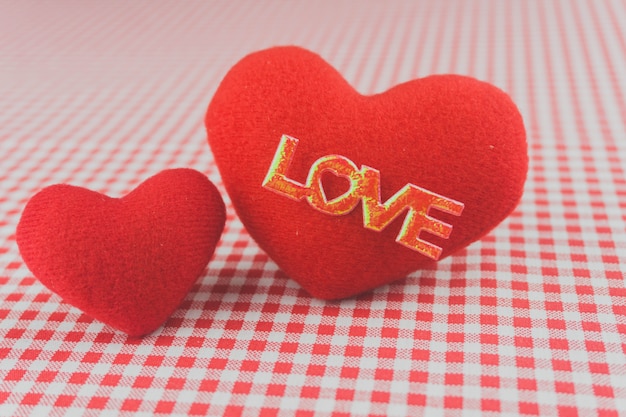 Plush hearts on a checkered tablecloth with the word "love"