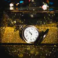 Бесплатное фото Карманные часы между золотыми блестками