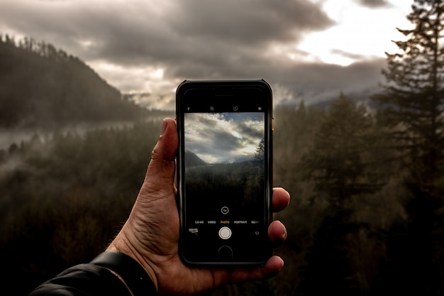 Point of view of a male holding a smartphone and taking a photo of a beautiful landscape