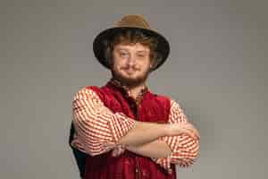 Free photo pointing. happy smiling man dressed in traditional austrian or bavarian costume gesturing isolated on grey studio