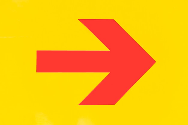 Free photo pointy red arrow on yellow background