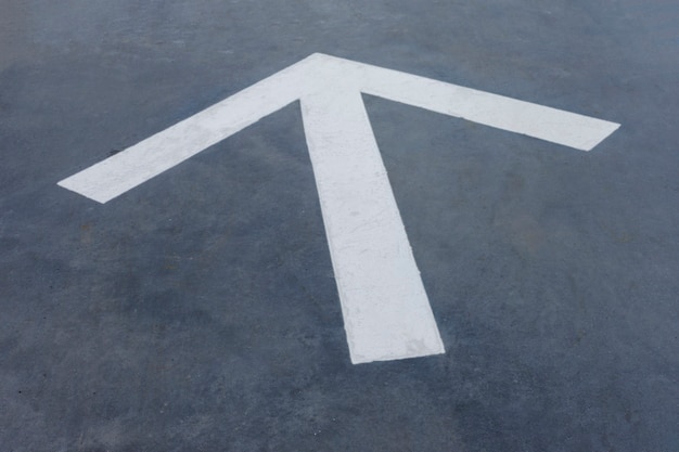 Free photo pointy white arrow on asphalt background