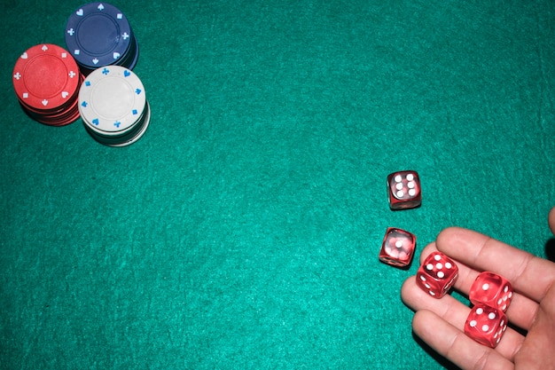 Poker player's hand throwing red dices on poker table