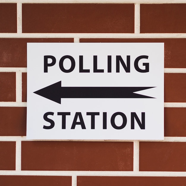 Polling station sign with direction on brick wall close-up