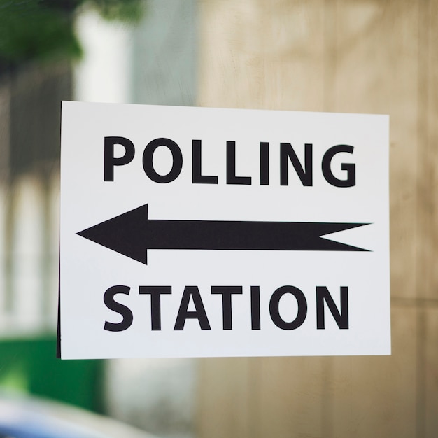 Polling station sign with direction on window close-up