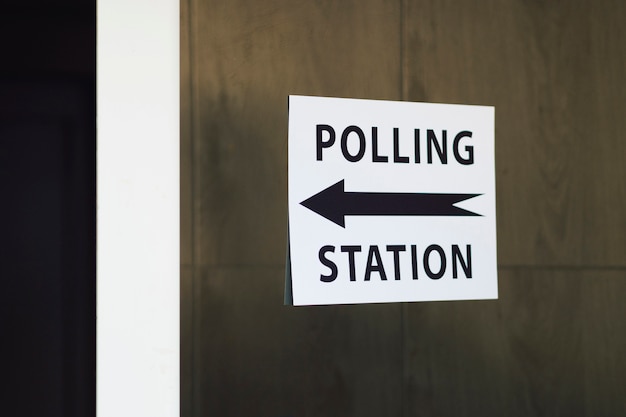 Polling station sign with direction on wooden wall 