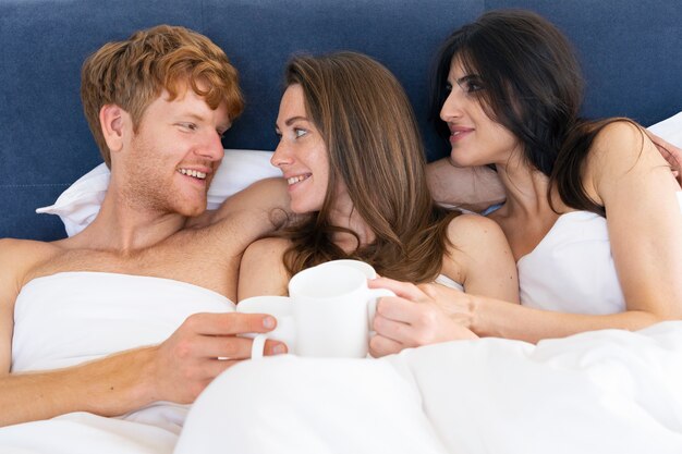 Polyamorous couple at home in bed