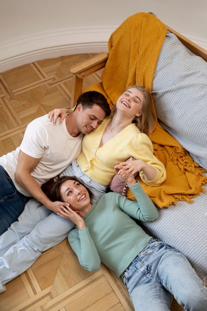 Polyamorous triad laying together medium shot