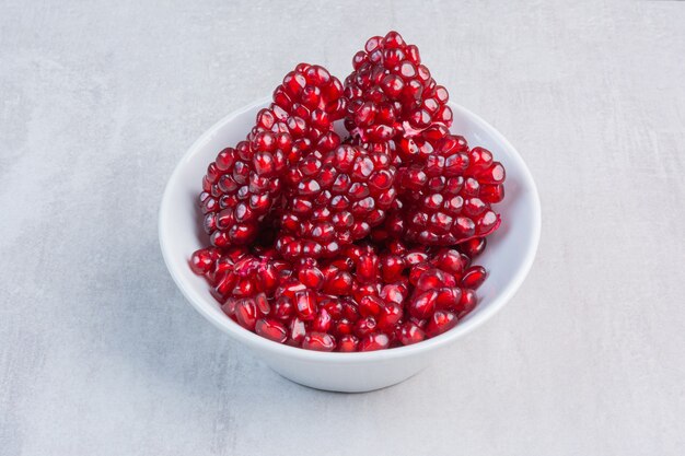 Pomegranate arils in a bowl , on the marble.