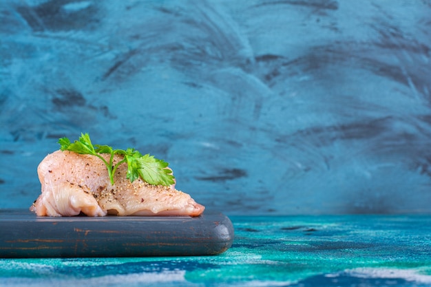 Pomegranate arils, lettuce leaves with onion ring next to chicken breast on a wooden tray 