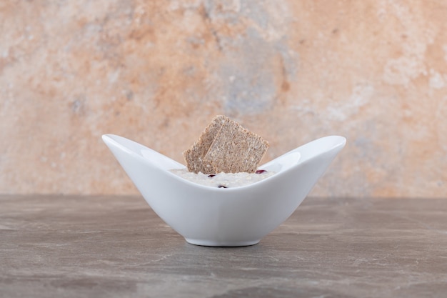Гранатовые зерна на каше в тарелке, на мраморной поверхности