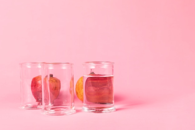 Pomegranate behind glasses filled with water