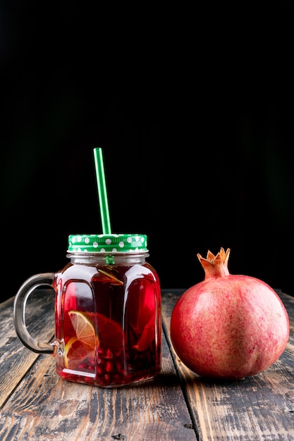 Free photo pomegranate juice in jar on wooden table