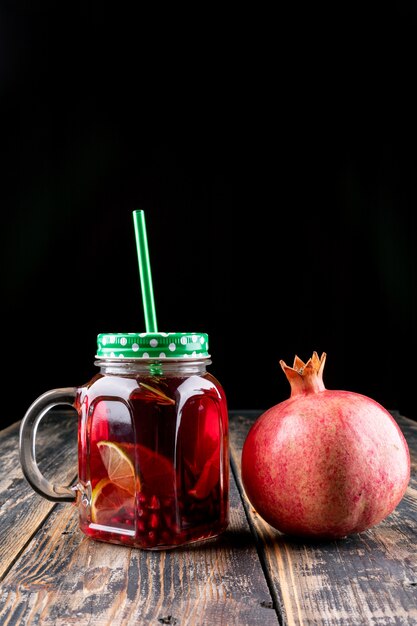 Pomegranate juice in jar on wooden table