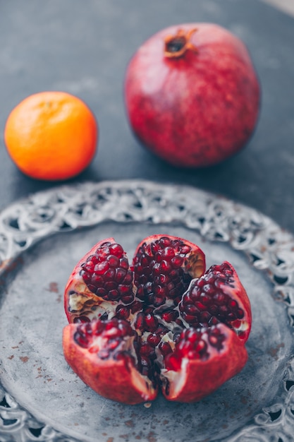 Pomegranate in plate with mandarin on dark