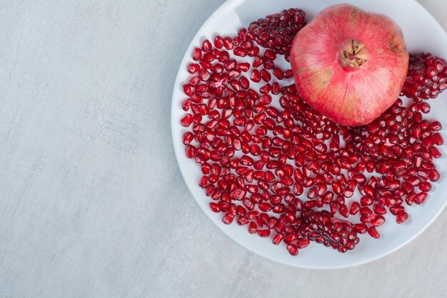 Pomegranate and pomegranate seeds on white plate. High quality photo