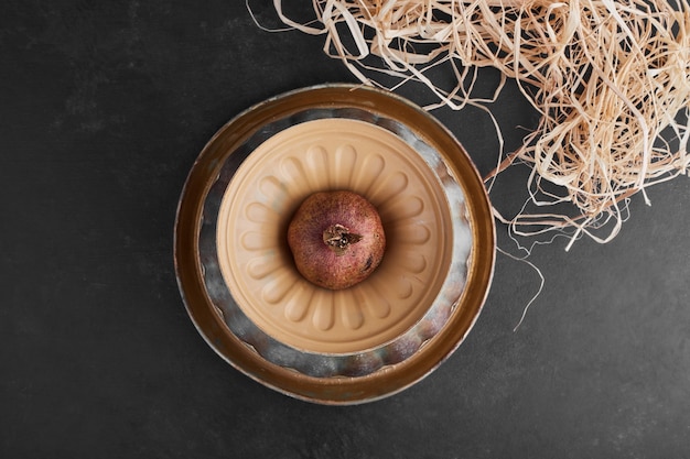 A pomegranate in a pottery bowl.