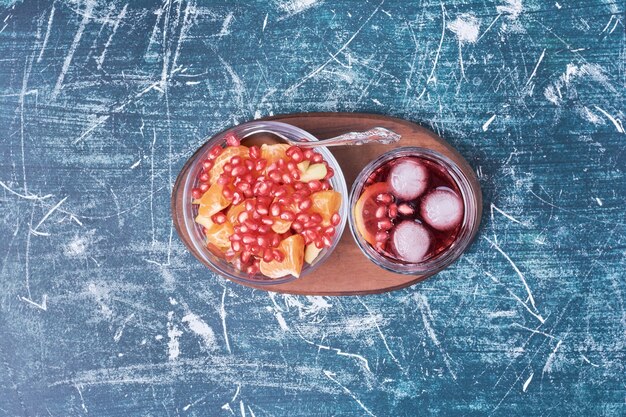 Pomegranate salad with a cup of drink on blue.