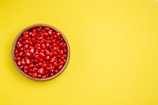 pomegranate seeds of the appetizing pomegranate in the bowl on the yellow table