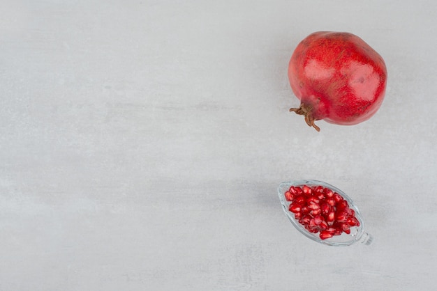 Pomegranate seeds in glass and pomegranate on white.