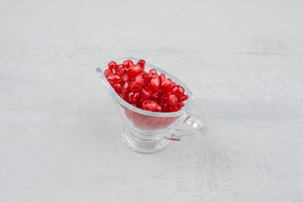 Pomegranate seeds in glass on white surface. 