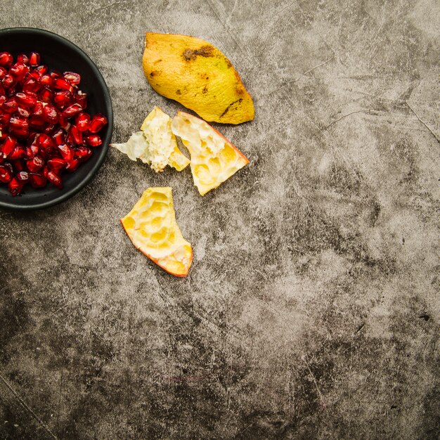 Pomegranate seeds and peel on stained background