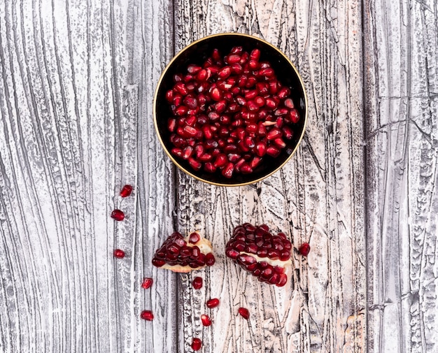 Free photo pomegranate seeds in plate top view on wooden table