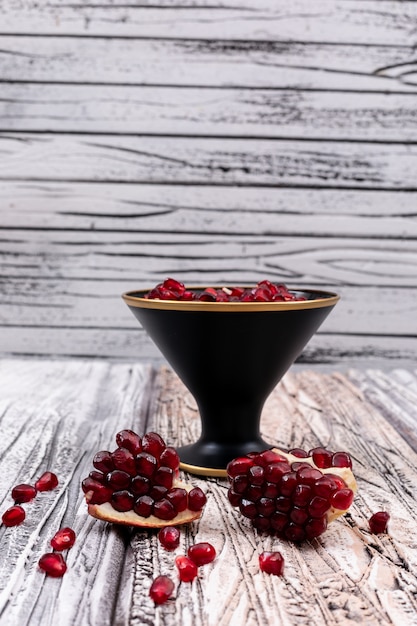 Free photo pomegranate seeds in plate on wooden table