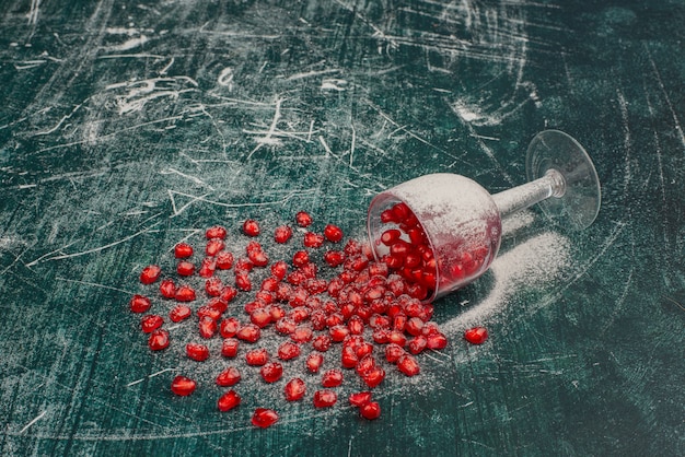 Free photo pomegranate seeds scattered on marble surface.