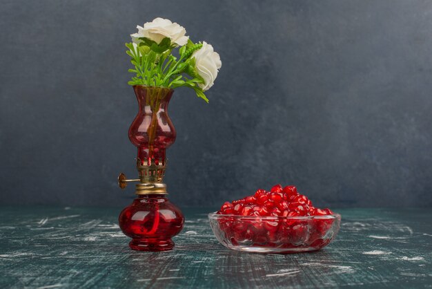 Pomegranate seeds and white flowers in vase.