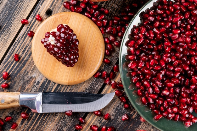 Pomegranate top view with knife on wooden surface