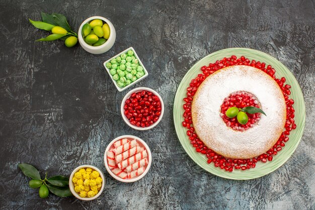 Foto gratuita torta di melograni con semi di melograno ciotole di lime dolci vari