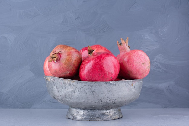 Pomegranates in a metal vase on marble background.