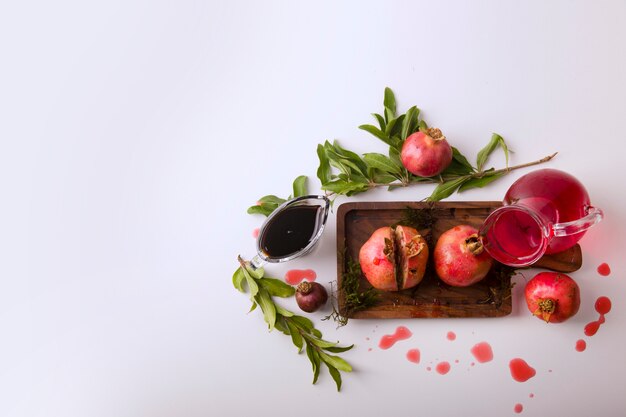 Pomegranates with red sauce and juice on a wooden board, top view