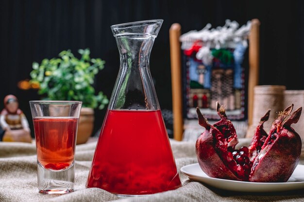 Pomegrante juice in the jug with the seeds inside fruit shot side view