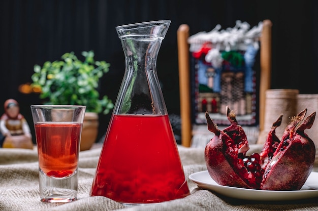 Pomegrante juice in the jug with the seeds inside fruit shot side view