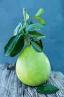 Foto gratuita pomelo con foglie verdi su una tavola di legno