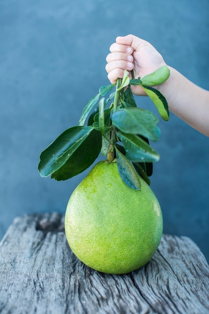 Pomelo with green leaves on a wooden board