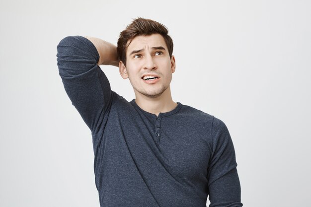 Pondering concerned man thinking, scratch back of head indecisive